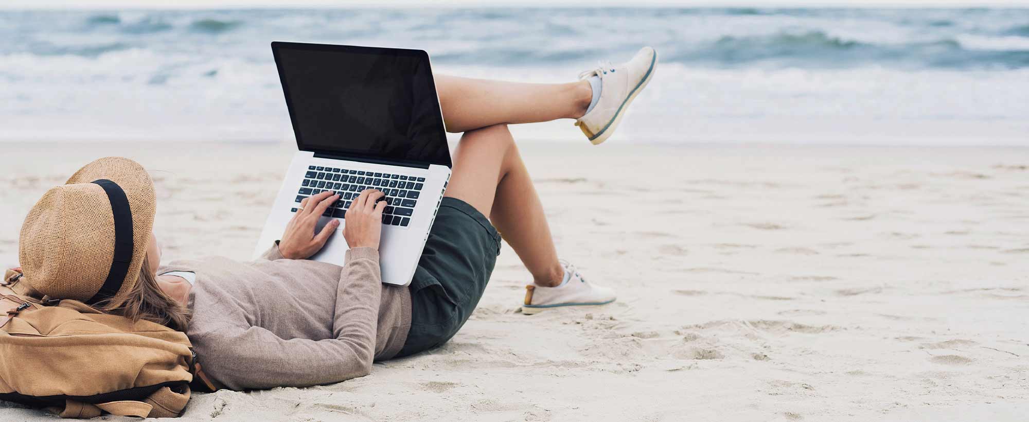 Lady relaxing on beach with laptop