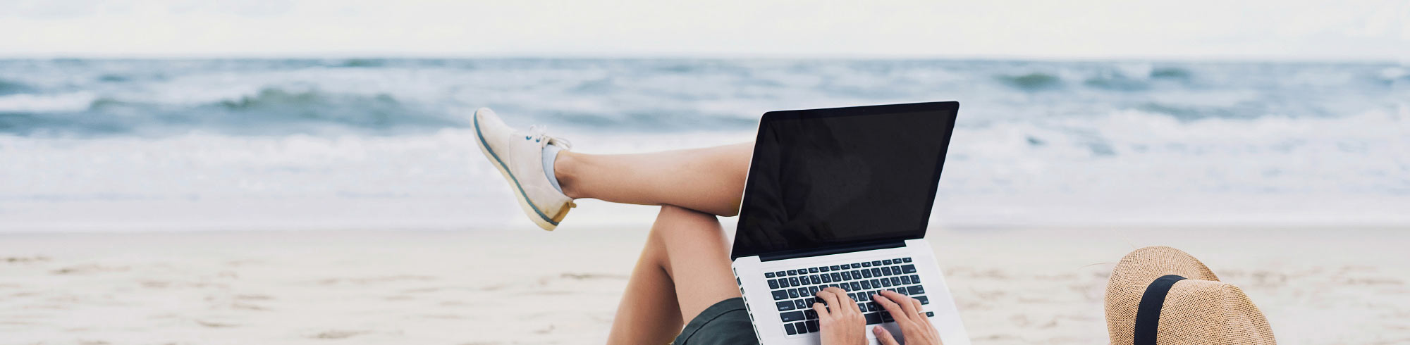 Person with laptop relaxing on a beach